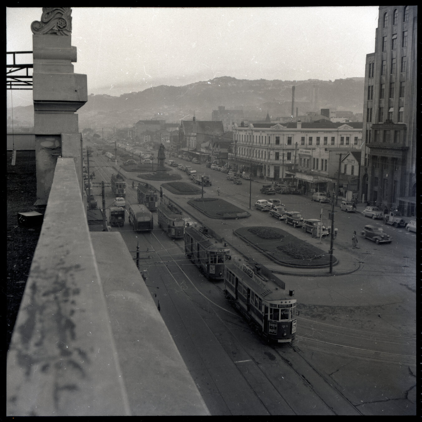 d. Elevated views of Courtenay Place, Cambridge and Kent Terrace from the top of the Embassy Theatre. Mens Toilet / Taj Mahal Restaurant, Tramcars, motor vehicles, Queen Victoria Statue, Cambridge Hotel 