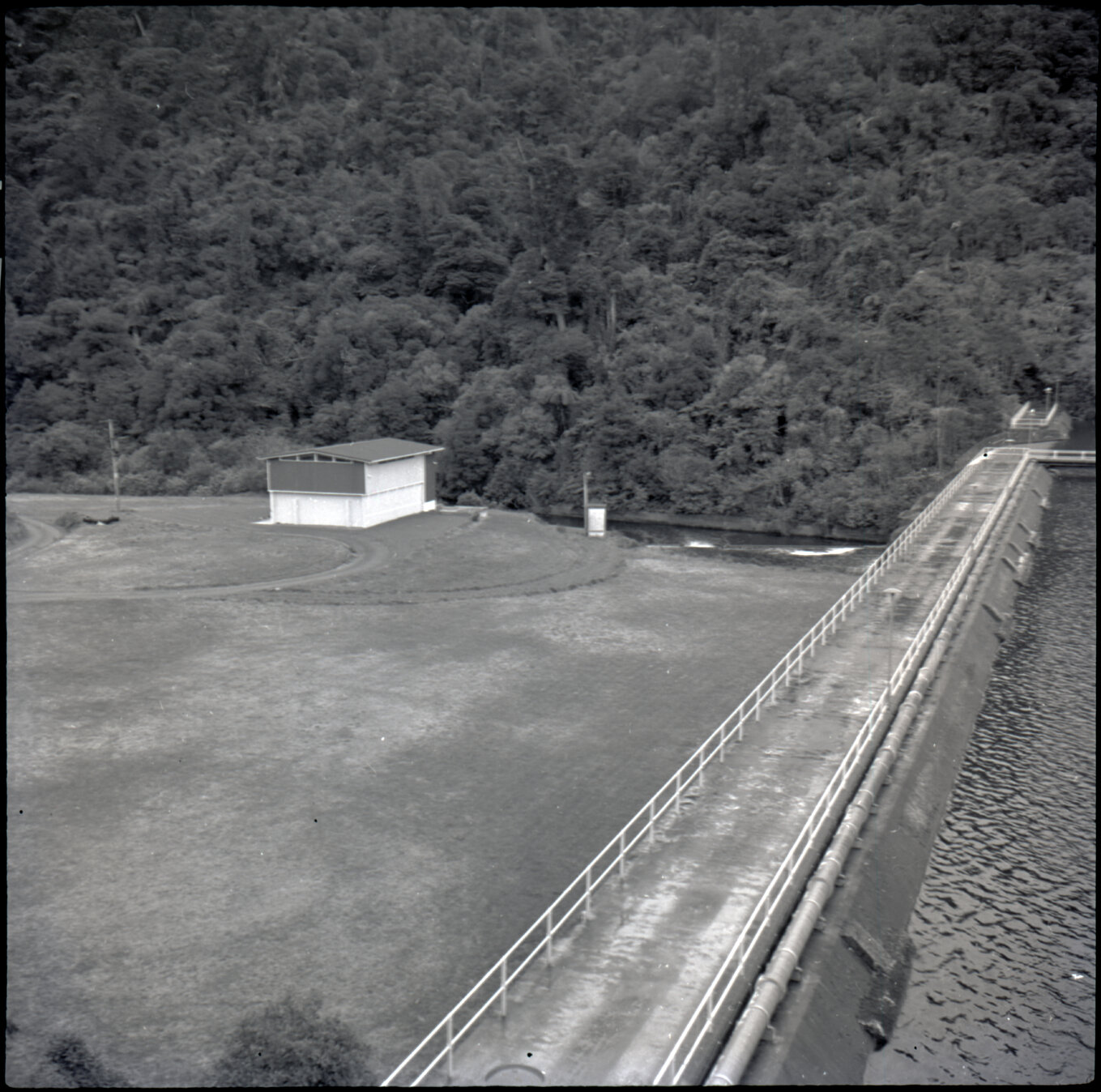 Orongorongo and Wainuiomata water catchment area, grassy area and building next to the dam