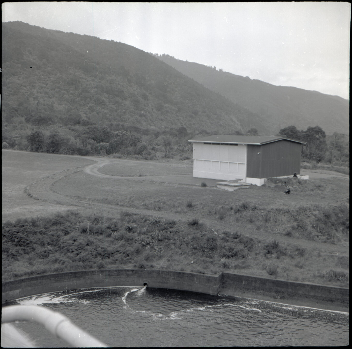 Orongorongo and Wainuiomata water catchment area, grassy area and building next to the dam