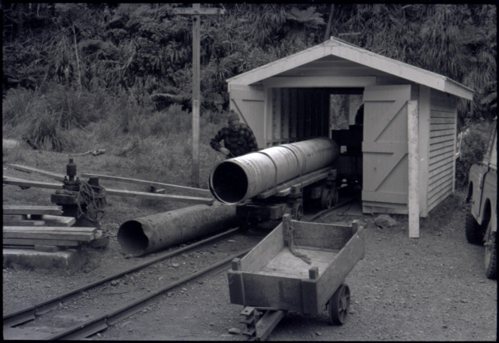 Orongorongo and Wainuiomata water catchment area, worker with a pipe going into a hut
