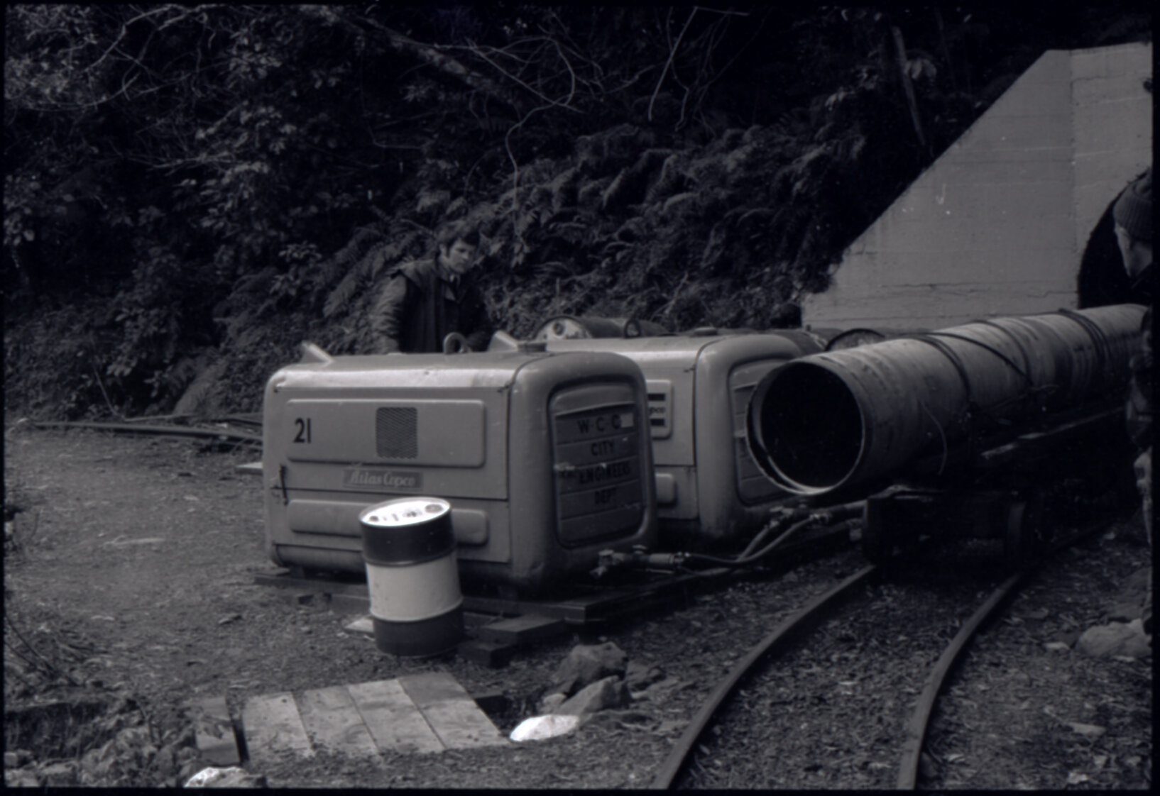 Orongorongo and Wainuiomata water catchment area, worker next to tunnel entrance with pipes