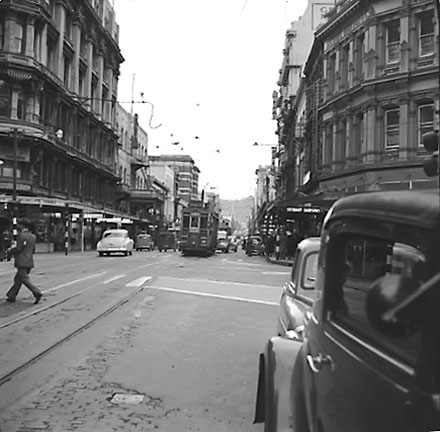 b. Pedestrians crossing road at corner of Courtenay Place and Blair Street. Diesel buses at bus stop in background