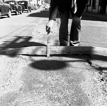 b. Workman pointing out damage / subsidence to road surface