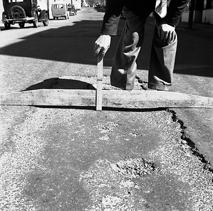 d. Workman pointing out damage / subsidence to road surface