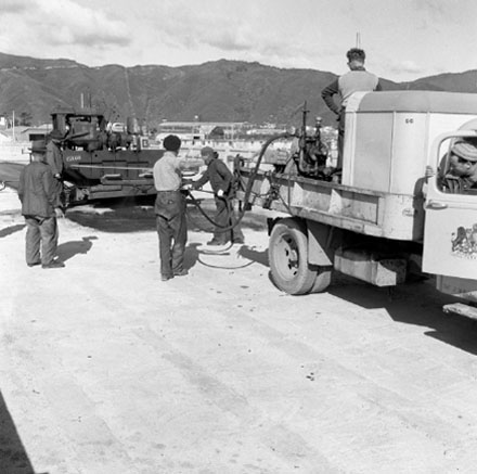 h. Construction of new bridge, workmen, machinery, motor vehicles. Road is being resurfaced