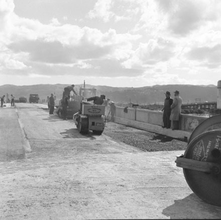 i. Construction of new bridge, workmen, machinery, motor vehicles. Road is being resurfaced