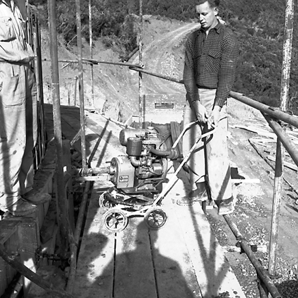 c. View of construction site, workmen are pouring concrete into framing