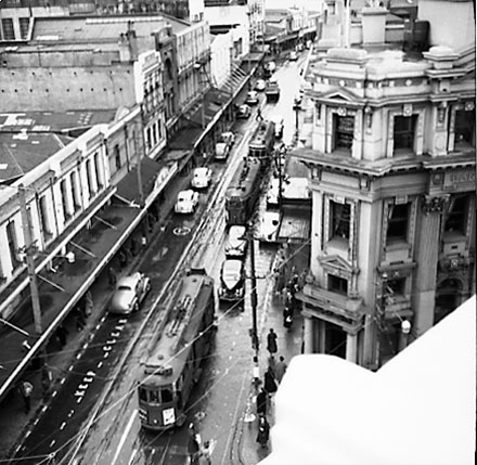 b. Elevated view of Manners Street from James Smith Corner. Bank of New Zealand on corner of Cuba Street. Motor vehicles and tramcars
