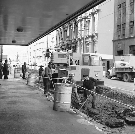 a. Looking east. Workmen are digging a trench, Gradall machine on back of a truck