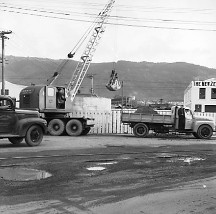 b. Looking south from Grey Street. Sightseeing bus is waiting to pull into the traffic, motor vehicles. Harbour Board Office and wharf sheds on left hand side of road. The Huddart Parker buidling is on the corner of Grey Street