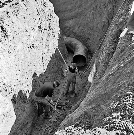 b. Workmen in trench laying pipes