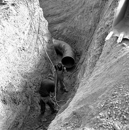 c. Workmen in trench laying pipes