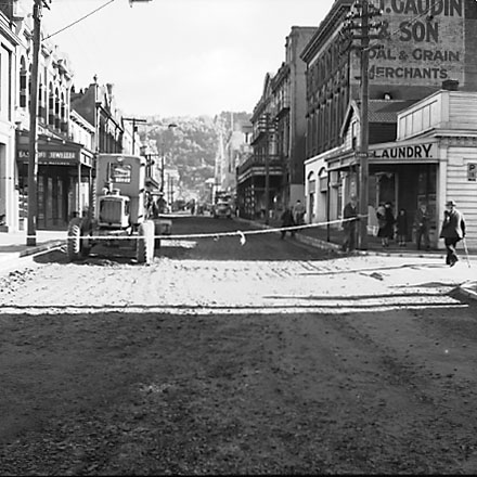 c. From the corner of Leeds Street, Ghuznee Street is being resurfaced. Buildings, motor vehicles, workmen