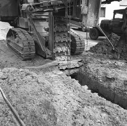 a. Workmen are using heavy machinery to dig trench in road