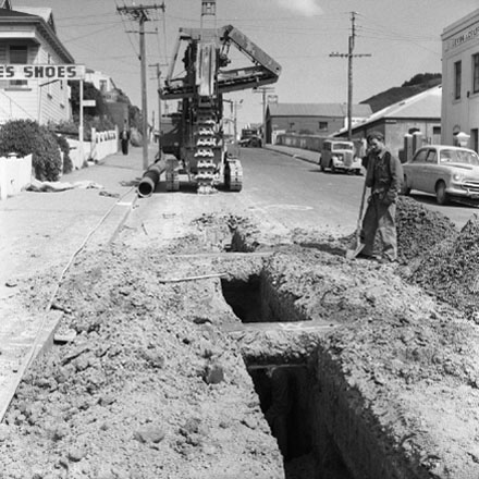 b. Workmen are using heavy machinery to dig trench in road