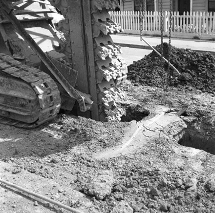 c. Workmen are using heavy machinery to dig trench in road