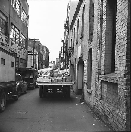 a. Motor vehicles / trucks parked in Herbert Street, commercial buildings. C R McKay, Sheet Metal Workers on the left on the corner of Edward Steet. Looking north towards Manners Street. Herbert Street became part of Victoria Street when Victoria Street w