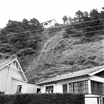 a. Slip in slope above building. Damage to building