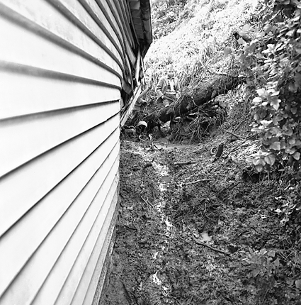 c. Slip in slope above building. Damage to building