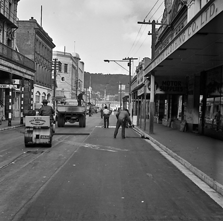 e. Looking east from Cuba Street to Taranaki Street intersection. Workmen are using an asphalt laying machine to re surface the road