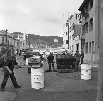 h. Looking east from Cuba Street to Taranaki Street intersection. Workmen are using an asphalt laying machine to re surface the road