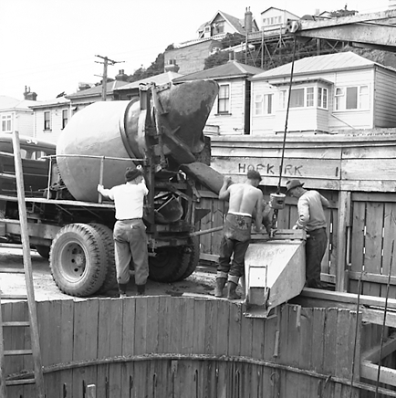 e. Workmen pouring concrete into base of underground pumping station
