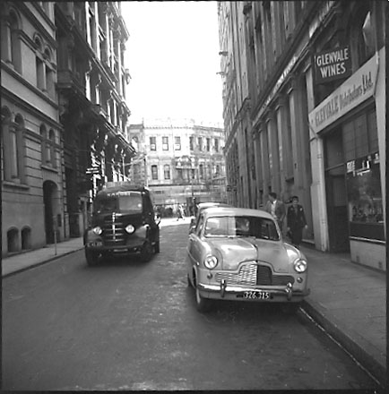 a. Looking west towards intersection with Willis Street. Commercial buildings, Glenvale Wines on right, Womens Rest Rooms on left. Motor Vehicles and truck. Workmen are painting the Stewart Dawsons building in the background