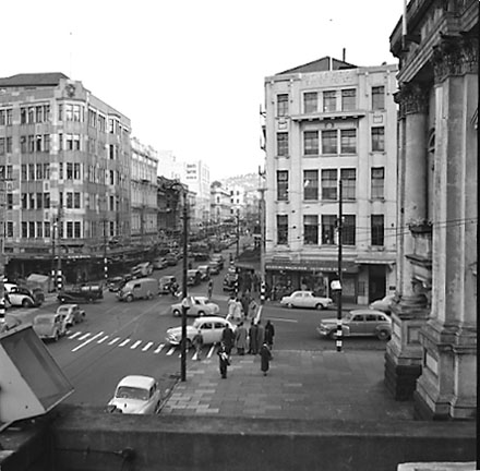 b. Elevated view of intersection, from roof of Town Hall Portico. Civic Chambers building (25-31 Cuba Street, 132-136 Wakefield Street) on the opposite corner, next to Anvil House (138-140 Wakefield Street) under construction. Motor vehicles, trolley bus,