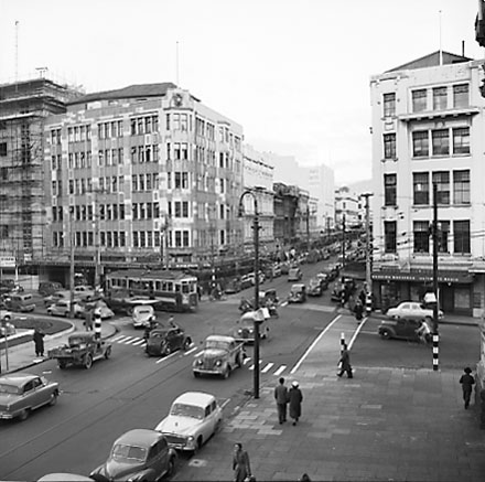 e. Elevated view of intersection, from roof of Town Hall Portico. Civic Chambers building (25-31 Cuba Street, 132-136 Wakefield Street) on the opposite corner, next to Anvil House (138-140 Wakefield Street) under construction. Motor vehicles, trolley bus,
