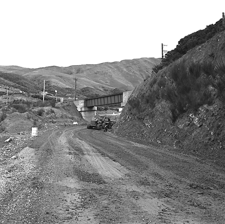 b. views of construction work in progress, workmen, equipment, graders, front end loaders, trucks, dwellings in the background