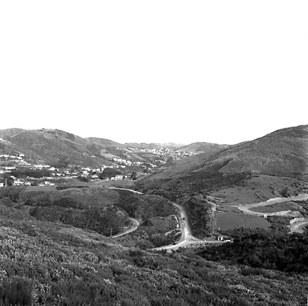 h. views of construction work in progress, workmen, equipment, graders, front end loaders, trucks, dwellings in the background