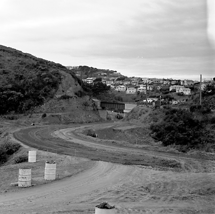 j. views of construction work in progress, workmen, equipment, graders, front end loaders, trucks, dwellings in the background