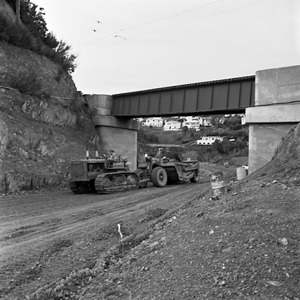 q. views of construction work in progress, workmen, equipment, graders, front end loaders, trucks, dwellings in the background