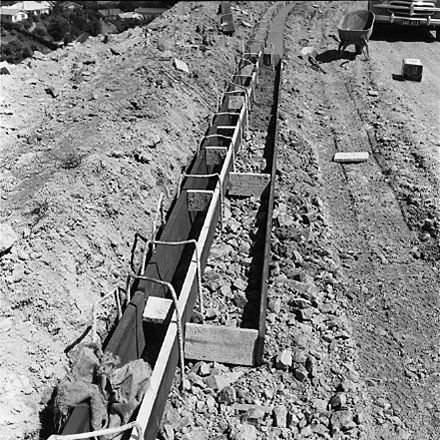 b. Road and kerb construction, motor vehicle in foreground. Workmen having break in background