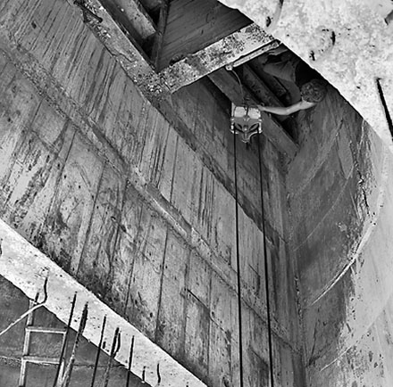 e. Workmen using crane truck to manoeuvre building materials into pumping station, interior of pumping station