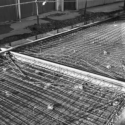a. Reinforcing has been laid, prior to new road surface being poured. Retail buildings in the background