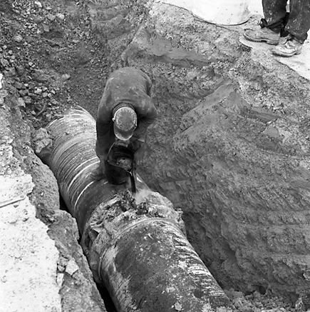 a. Workmen pouring molten material around join in pipes