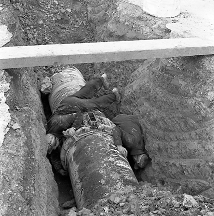 b. Workmen pouring molten material around join in pipes