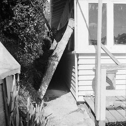 h. Views of dwelling that has been affected by a slip. Concrete retaining wall has fallen over against the house