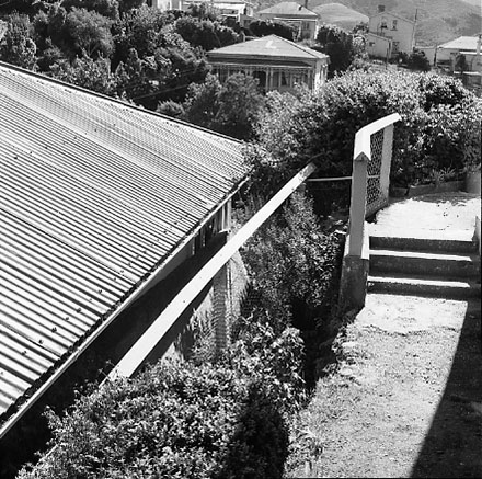 j. Views of dwelling that has been affected by a slip. Concrete retaining wall has fallen over against the house