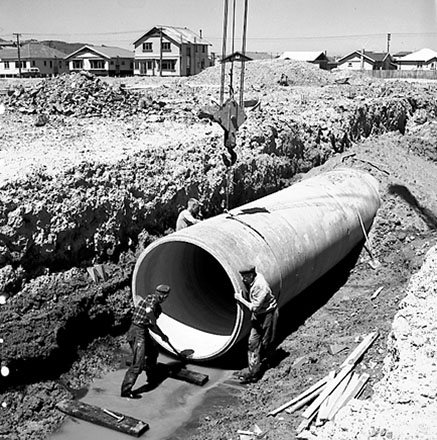 a. Workmen are using a crane to manouver drainage pipes into place