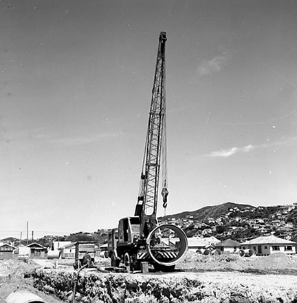 e. Workmen are using a crane to manouver drainage pipes into place