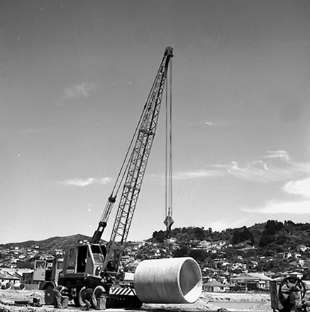 g. Workmen are using a crane to manouver drainage pipes into place