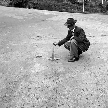 d. Workman pointing out damage to road surface
