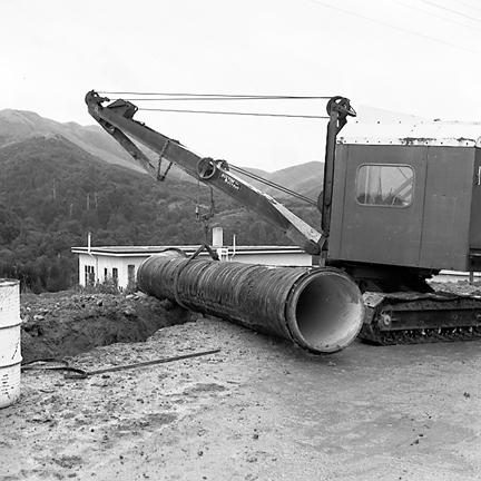 e. Views of workmen using a crane to install a new drainage pipe into trench