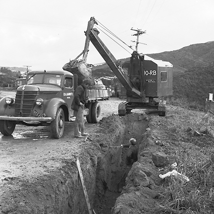 f. Views of workmen using a crane to install a new drainage pipe into trench