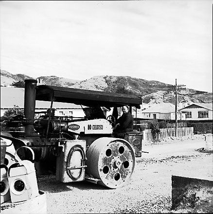 a. Workman operating roller, compacting road fill