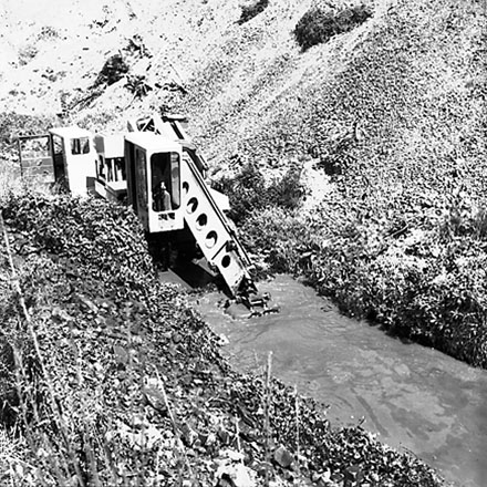 a. Gradall, large machine with scoop on front, clearing a trench