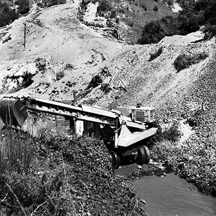 c. Gradall, large machine with scoop on front, clearing a trench