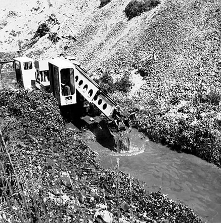 d. Gradall, large machine with scoop on front, clearing a trench